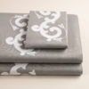 Completo di lenzuola in cotone percalle grigio rifinito con ricamo bianco e raso di cotone in applicazione su lenzuolo superiore e federe.